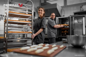 Chefs working in a professional New Zealand restaurant kitchen with commercial refrigeration, baking racks and food preparation equipment